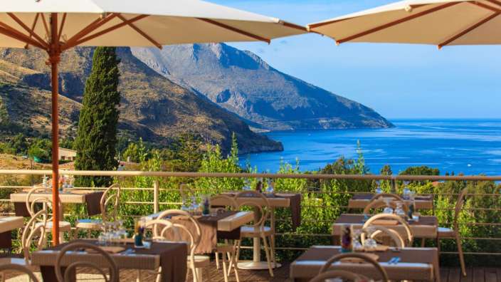 Tische und Stühle auf einer Terrasse mit Blick auf den Ozean