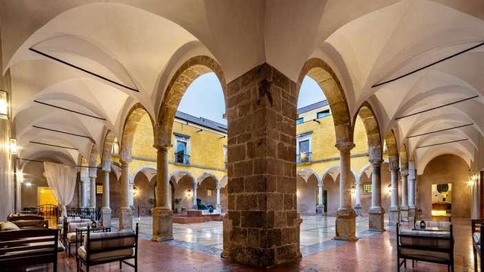 Ein Gebäude mit vielen Steinbögen und Stühlen