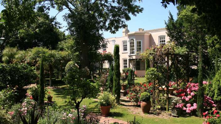 Ein Garten mit einem rosa Haus im Hintergrund