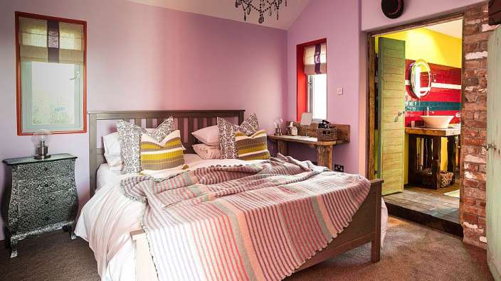 Ein Schlafzimmer mit lila Wänden und einem Bett