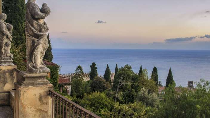 Eine Statue steht auf einem Balkon mit Blick auf das Meer