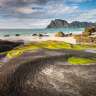 Ein felsiger Strand mit Bergen im Hintergrund
