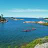 Zwei Menschen paddeln in roten Kajaks auf einem See
