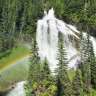 Ein Wasserfall im Wald mit einem Regenbogen davor