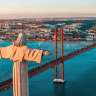 Die Statue Christi des Königs steht über der Stadt Lissabon mit der Ponte 25 de Abril im Hintergrund bei Sonnenaufgang.