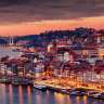 Eine malerische Aufnahme der Stadt Porto bei Sonnenuntergang, mit dem Douro-Fluss im Vordergrund und der charakteristischen Architektur im Hintergrund.