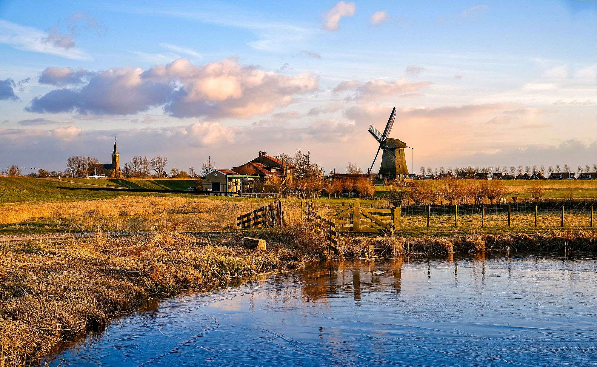 Eine Windmühle steht in einem Feld neben einem Fluss