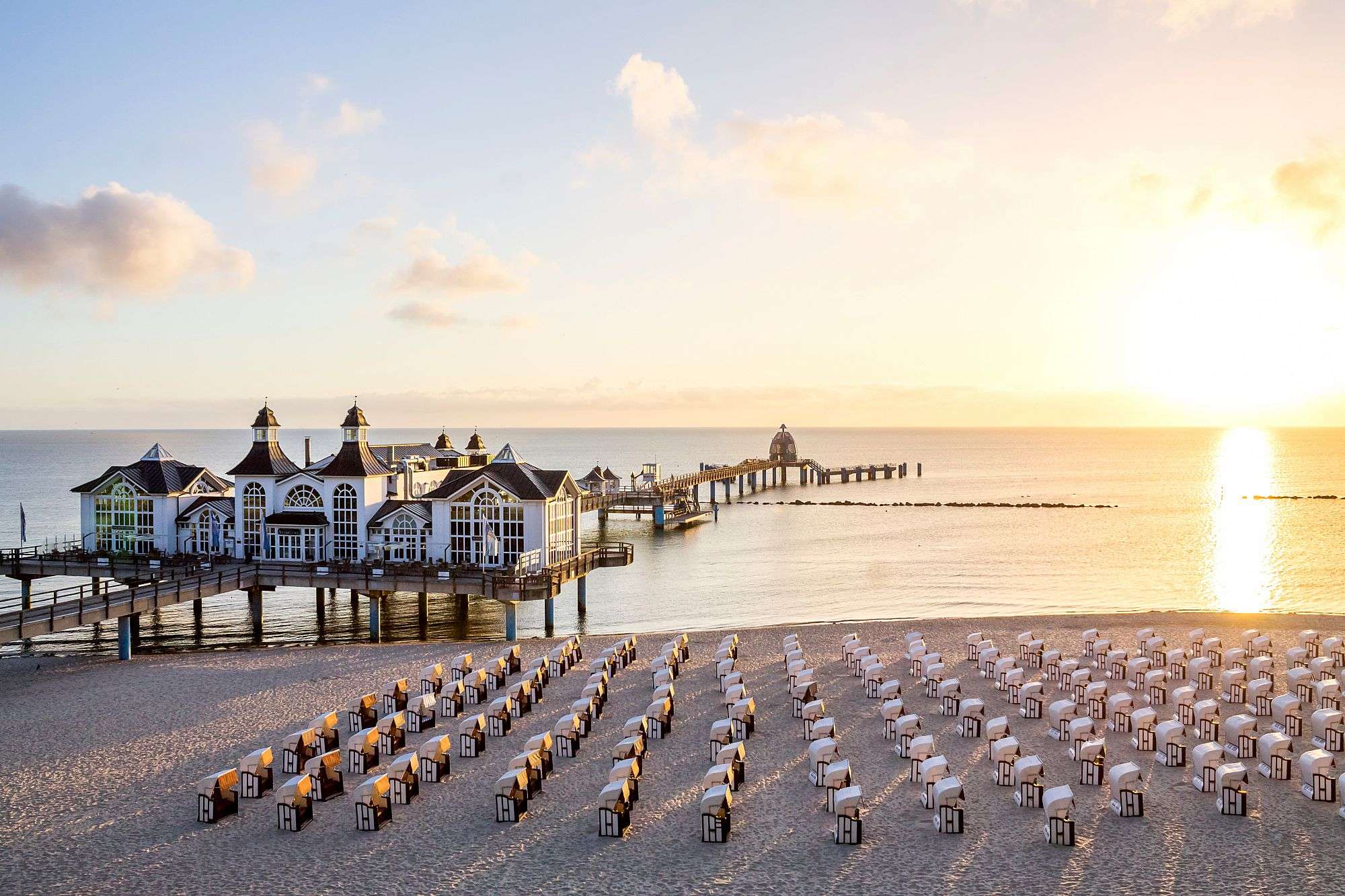 Ein Strand mit vielen Strandkörben und einem Gebäude im Hintergrund