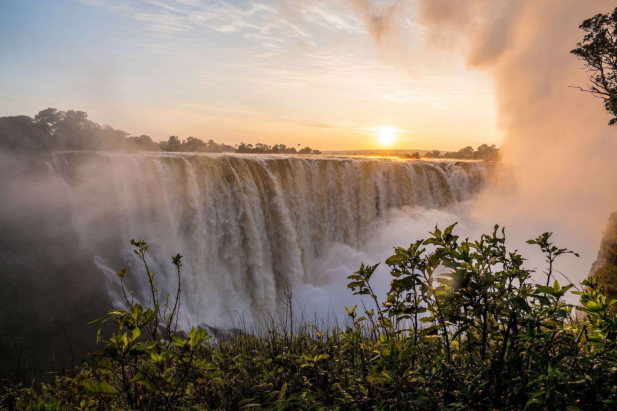 Die Sonne geht hinter einem Wasserfall unter