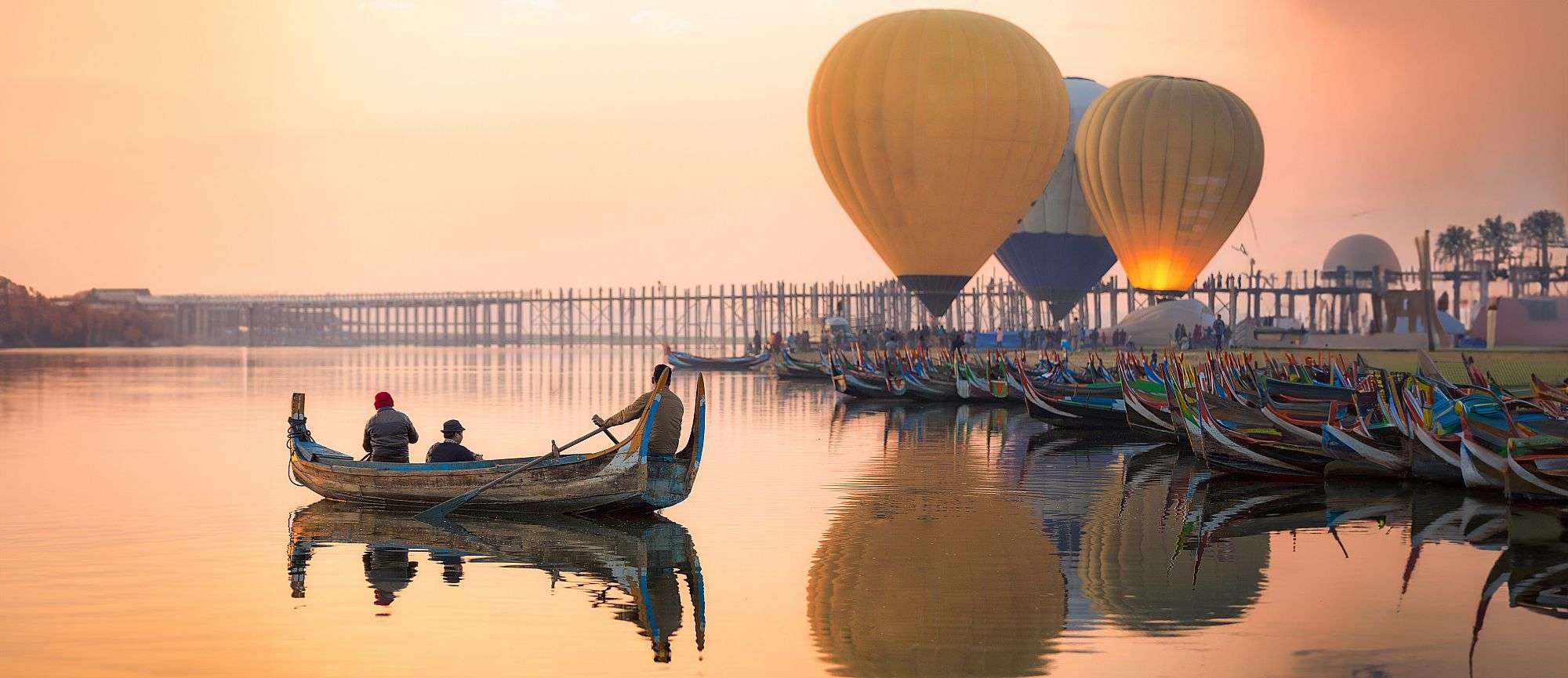 Menschen in einem Boot mit Heißluftballons im Hintergrund