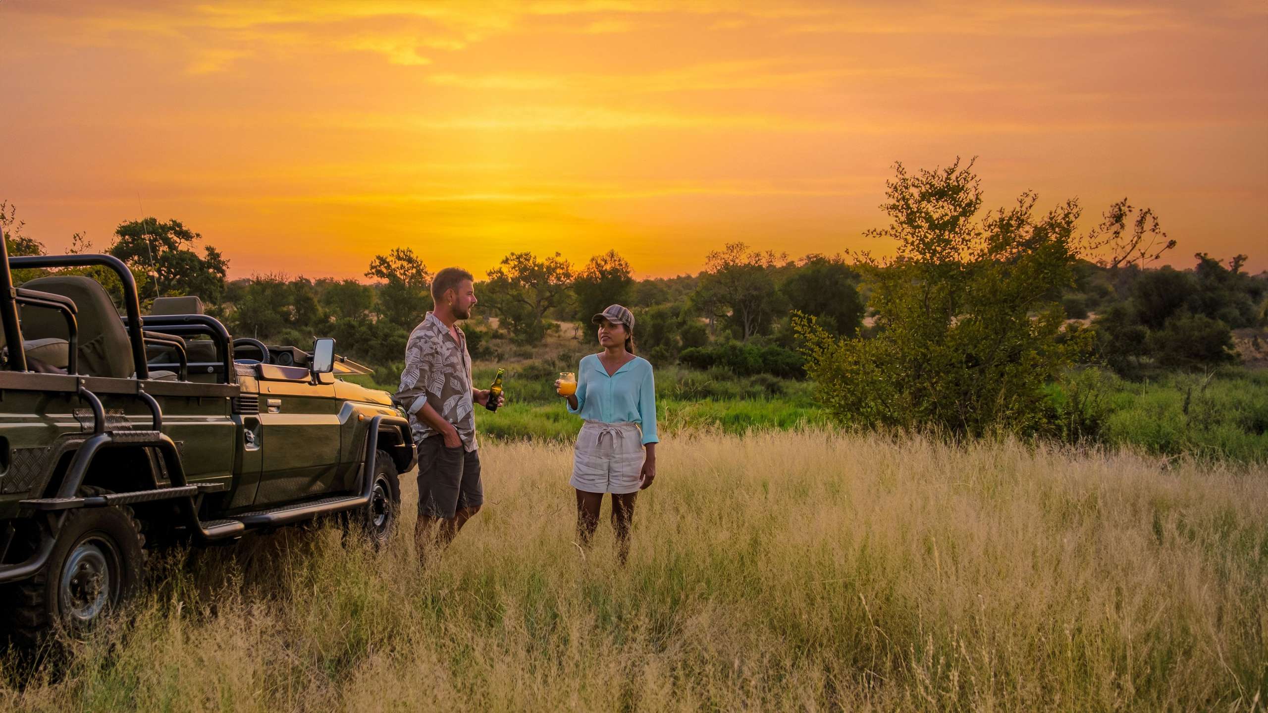 Ein Mann und eine Frau stehen in einem Feld vor einem Jeep
